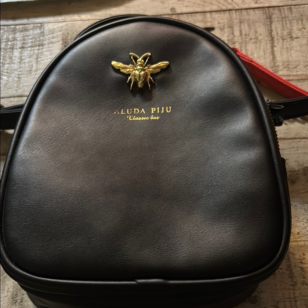 Elegant Black and Gold Backpack with Smooth Finish and Prominent Emblem